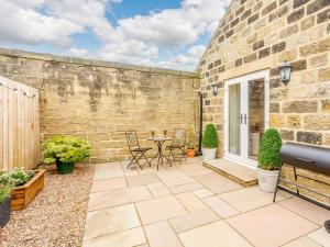 a patio with a table and chairs next to a brick wall at 1 Bed in Pateley Bridge 89152 in Summer Bridge