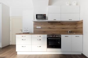 cocina con armarios blancos y microondas en Old Town Square Residence by Emblem, en Praga