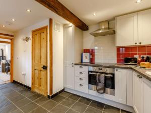 uma cozinha com armários brancos e um forno com placa de fogão em 2 Bed in Umberleigh 54354 em Atherington