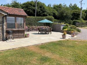 a patio with a table and an umbrella at 2 Bed in Cheddar TFORG in Butcombe