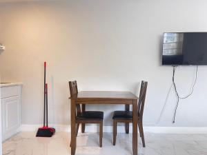 a wooden table with two chairs and a television at Studio Apartment By Pmi Edgewood in Fort Lauderdale