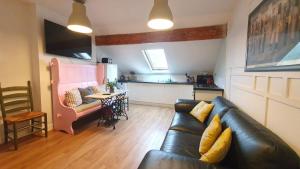 a living room with a black leather couch and a kitchen at The Loft at York House in Birmingham