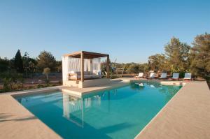 a swimming pool with a gazebo next to a house at Ibiza Holliday Villa Harmony in Sant Jordi