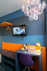 a room with a desk with a purple chair and a tv at Hotel Gabriel in Le Mont Saint Michel