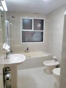 a bathroom with a tub and a sink and a toilet at ETAS Residence in Abu Dhabi
