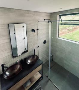 uma casa de banho com 2 lavatórios e uma cabina de duche em vidro. em The Villa at 40 Acres - Spacious Luxury Farmhouse on 16 hectares em Magaliesburg