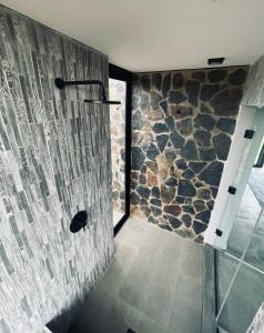 uma casa de banho com um chuveiro e uma parede de pedra em The Villa at 40 Acres - Spacious Luxury Farmhouse on 16 hectares em Magaliesburg