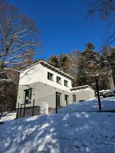 una casa blanca con nieve delante en The Houses - Chata u sjezdovky 1 en Velké Meziříčí