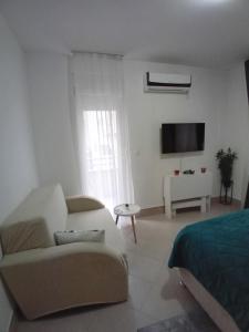 a white living room with a couch and a tv at Wing Nina2 in Jagodina