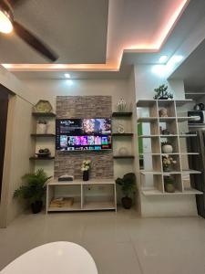 Amaze Staycation Makati في مانيلا: غرفة معيشة مع تلفزيون على جدار من الطوب