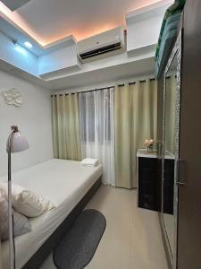 Amaze Staycation Makati في مانيلا: غرفة نوم صغيرة بها سرير ونافذة
