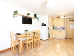 a kitchen with a table and chairs and a refrigerator at Duplex pour 4 pers. avec balcon, proche centre et téléphérique, parking & casier à skis - FR-1-296-128 in Saint-Lary-Soulan