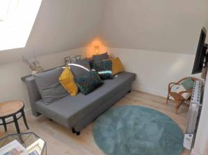 a living room with a gray couch with colorful pillows at Le loft d'Adrien, une ode à la douc'Eure, classé 3 étoiles, accueil vélo in Beauficel-en-Lyons