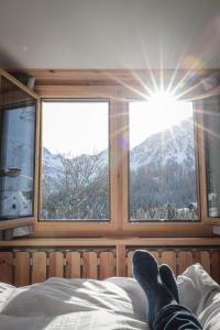 a person laying on a bed looking out the window at Hotel Garni Sonnenhalde in Arosa