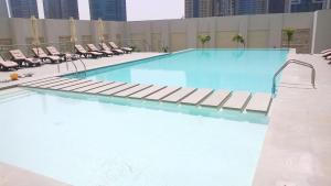 uma grande piscina com espreguiçadeiras num edifício em New Stylish 1 BD in West Avenue Marina em Dubai