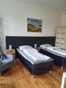 dwa łóżka i krzesło w pokoju w obiekcie Kamienica Nowodworska 30 w Bydgoszczy