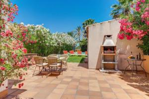 eine Terrasse mit einem Grill, Stühlen und Blumen in der Unterkunft Villa Casa de Lago by Villa Plus in Playa de Muro