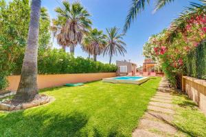 einen Garten mit Pool und Palmen in der Unterkunft Villa Casa de Lago by Villa Plus in Playa de Muro
