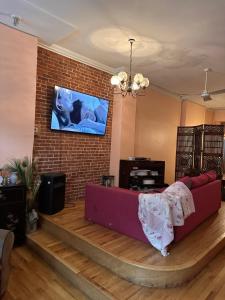 uma sala de estar com um sofá e uma televisão numa parede de tijolos em Macaw Guest House em Nova York