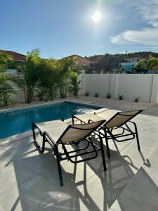 a table and chairs sitting next to a swimming pool at Villa Vista Montaña in Willemstad
