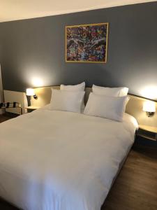 duże białe łóżko w pokoju z 2 lampami w obiekcie Grand Hôtel d'Espagne w Lourdes