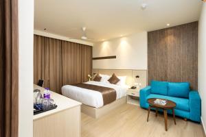 a hotel room with a bed and a blue couch at PRESIDENCY AIRPORT HOTEL in Cochin