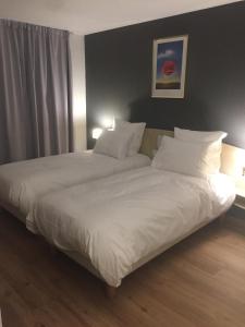 1 cama con sábanas blancas y almohadas en una habitación en Grand Hôtel d'Espagne, en Lourdes