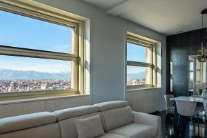 uma sala de estar com um sofá e duas janelas em Prestige Apartments Torino em Turim