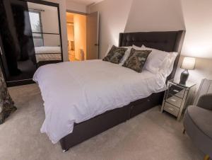 una camera da letto con un grande letto con lenzuola e cuscini bianchi di Coastal Cove a Poole