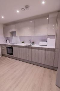 uma cozinha com armários brancos e piso em madeira em Coastal Cove em Poole