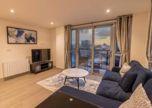 ein Wohnzimmer mit einem blauen Sofa und einem TV in der Unterkunft Coastal Cove in Poole