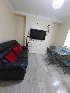 a living room with a black couch and a tv at House In the heart of valleys in Ebbw Vale