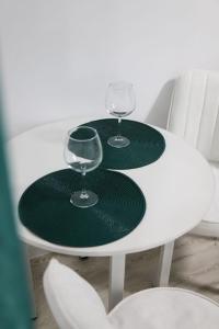 two green plates and glasses on a white table at Апартаменты в ЖК Каркын in Kostanay