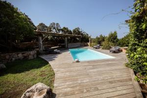 a backyard with a swimming pool and a wooden deck at Casa Laricciu in Figari