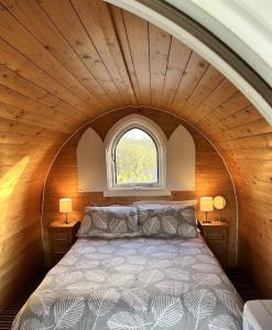 een bed in een kleine kamer met een raam bij Blackbrook lodge Camping pods in Belper