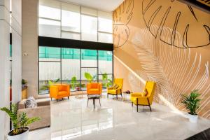 an office lobby with orange chairs and a wall of windows at PRESIDENCY AIRPORT HOTEL in Cochin