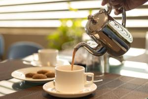 a person is pouring coffee into a cup on a table at PRESIDENCY AIRPORT HOTEL in Cochin