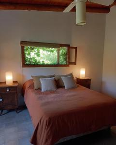 a bedroom with a bed with two night stands and a window at Casa.Colibri.LaCumbre in La Cumbre