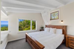 a white bedroom with a bed and a window at Piha - City Escape, Piha Holiday Home in Piha