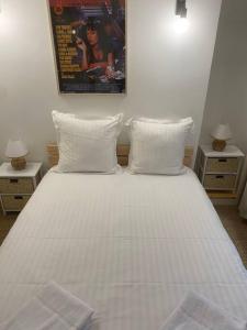 1 dormitorio con 1 cama blanca y 2 mesitas de noche en Coeur de Jaude 2 chambres Tout équipé 4 personnes, en Clermont-Ferrand