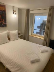 1 dormitorio con 1 cama blanca y 2 toallas en Coeur de Jaude 2 chambres Tout équipé 4 personnes, en Clermont-Ferrand
