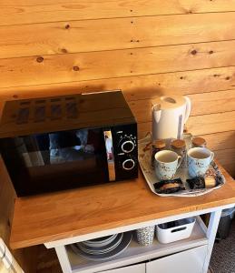 a microwave on a table with cups and plates at Blackbrook lodge Camping pods in Belper