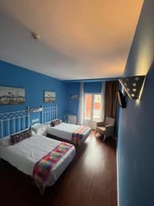 a blue room with two beds and a chair at Orquídea Real in Villablino