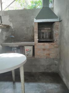 um forno de tijolos com uma mesa branca em frente em Casa Toque toque pequeno em São Sebastião