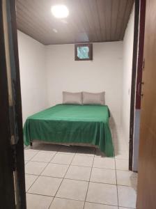 um quarto com uma cama com um lençol verde em Casa Toque toque pequeno em São Sebastião
