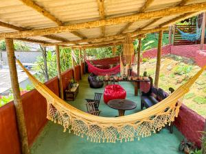 an outdoor porch with a hammock and a table and chairs at Pousada Pedra Alta in Itacaré