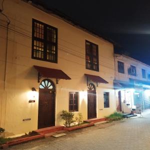 ein weißes Gebäude mit braunen Türen und Fenstern in der Nacht in der Unterkunft Sundance Beach Villa Dorms in Kochi