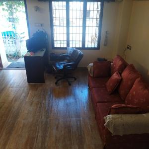 ein Wohnzimmer mit einem Sofa, einem Schreibtisch und einem Computer in der Unterkunft Sundance Beach Villa Dorms in Kochi