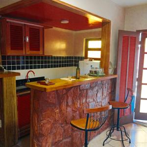 a kitchen with a stone counter and two bar stools at Super Flats Geribá in Búzios