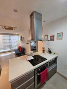 a kitchen with a stove top oven next to a living room at Apartamento Bello Horizonte in Santa Marta
